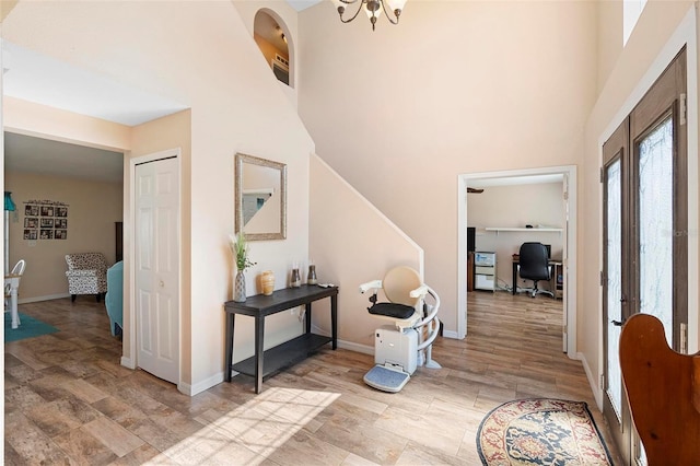 foyer entrance featuring a towering ceiling, light wood finished floors, and baseboards