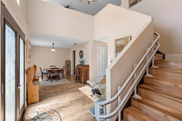 stairs with a high ceiling, wood finished floors, visible vents, and baseboards