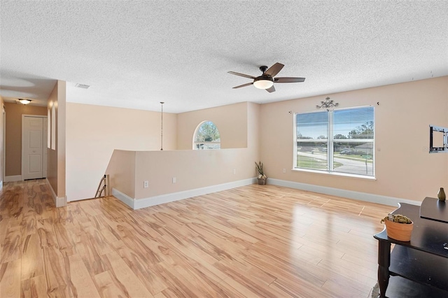 unfurnished living room with a textured ceiling, a healthy amount of sunlight, and light wood-style floors