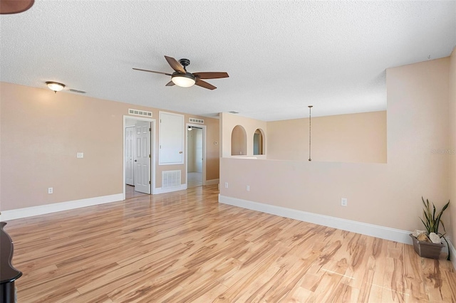 spare room with light wood finished floors, ceiling fan, and visible vents