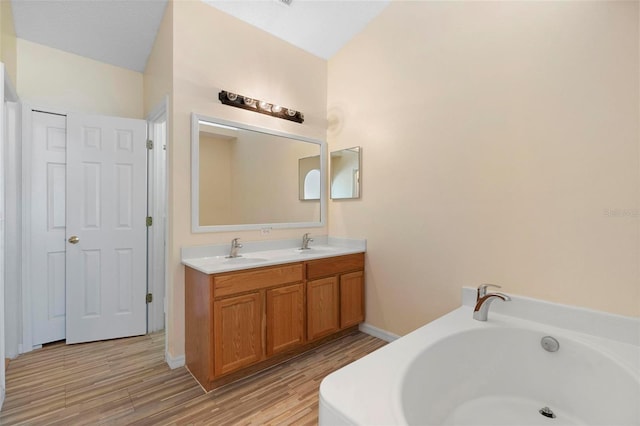 full bathroom featuring wood finished floors, double vanity, a sink, and a bath