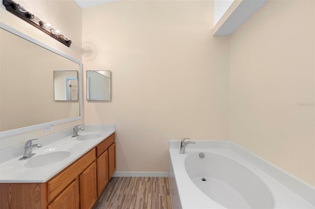 bathroom featuring a bath, double vanity, a sink, and wood finished floors