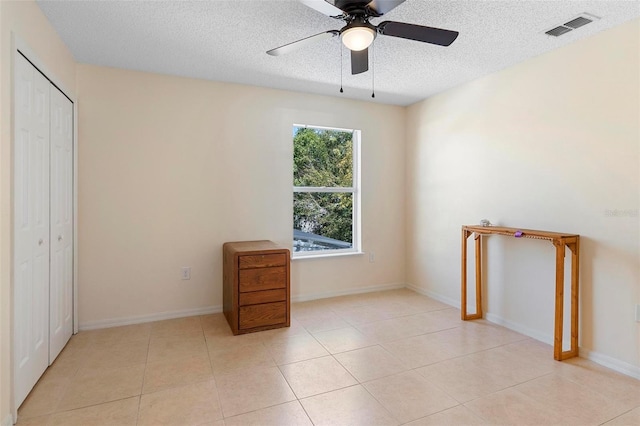 spare room featuring light tile patterned floors, visible vents, baseboards, ceiling fan, and a textured ceiling