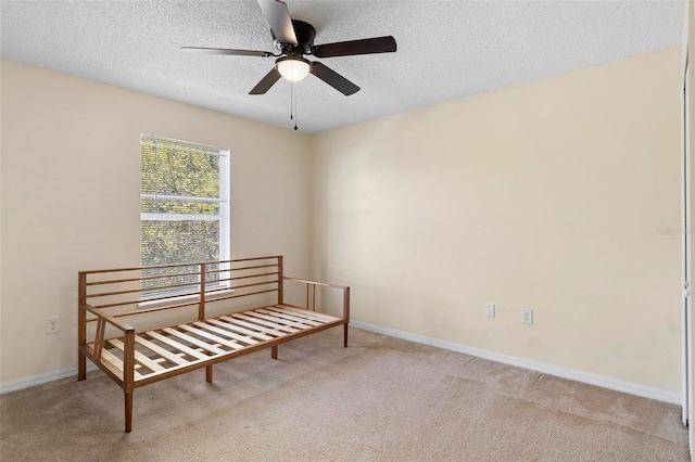 sitting room with a textured ceiling, ceiling fan, carpet flooring, and baseboards