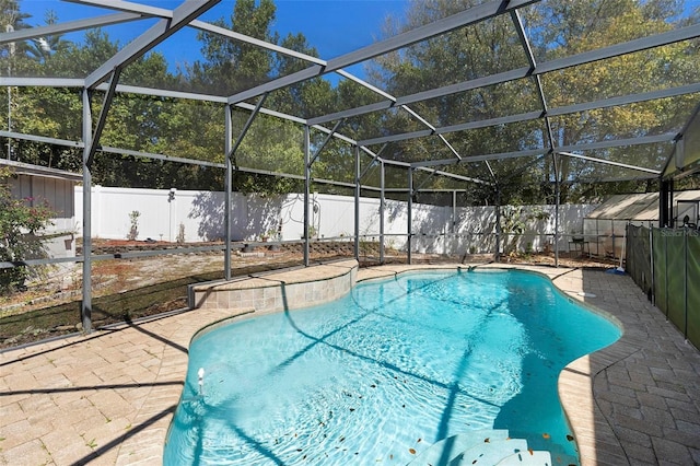 view of pool featuring a patio, glass enclosure, a fenced backyard, and a fenced in pool