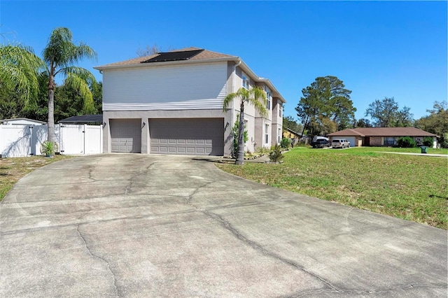 view of home's exterior with a yard, solar panels, a gate, fence, and a garage