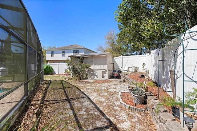 view of yard featuring a lanai, a storage shed, a fenced backyard, and an outdoor structure