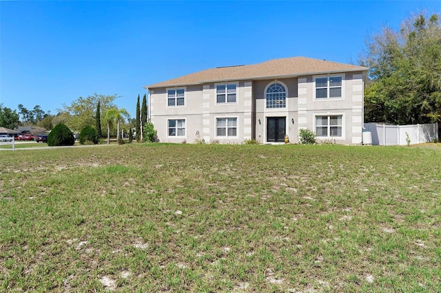 view of front of house with a front yard, fence, and stucco siding