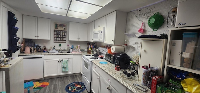 kitchen with wood finished floors, white appliances, a sink, and white cabinets