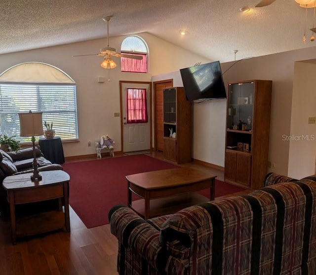 living area featuring ceiling fan, a textured ceiling, vaulted ceiling, and wood finished floors