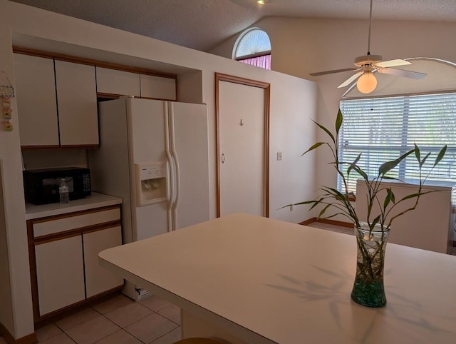 kitchen with black microwave, lofted ceiling, white refrigerator with ice dispenser, white cabinetry, and light countertops