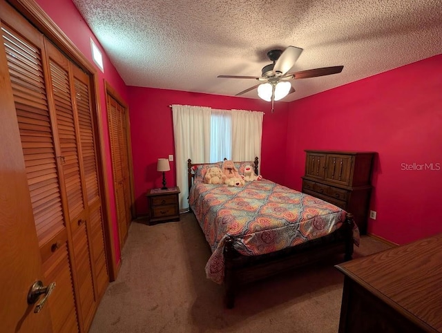 bedroom featuring two closets, carpet, ceiling fan, and a textured ceiling