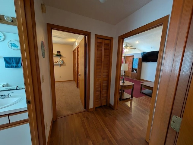 corridor with a sink, wood finished floors, and baseboards