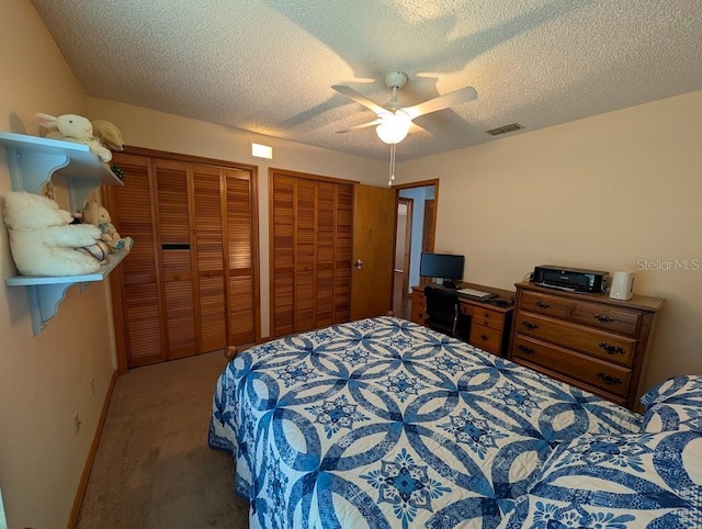 carpeted bedroom with a textured ceiling, a ceiling fan, visible vents, and multiple closets