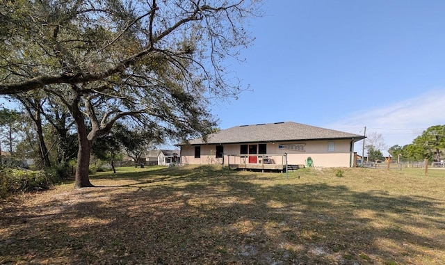 back of house with a lawn, a wooden deck, and stucco siding