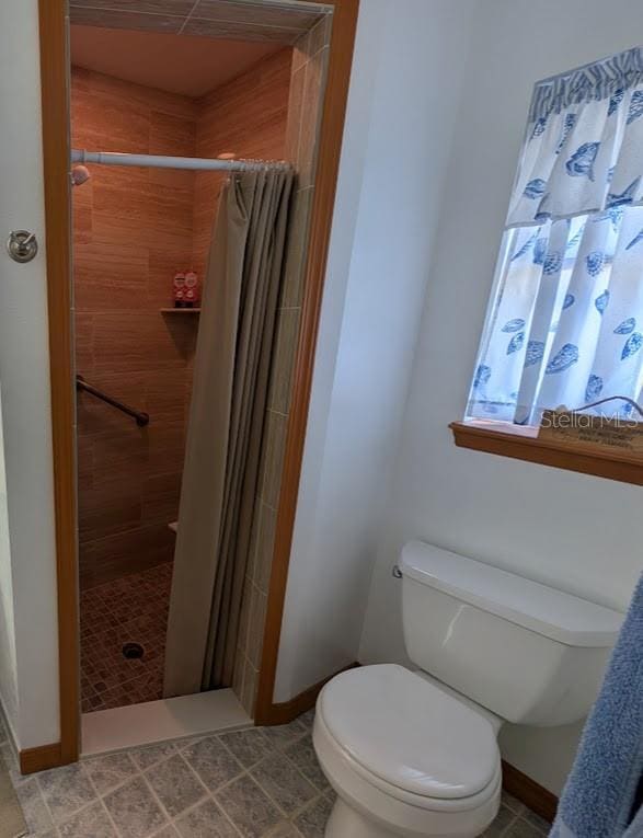 full bath featuring a stall shower, toilet, and baseboards