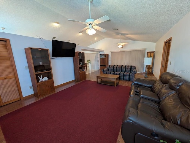 living room with a ceiling fan, vaulted ceiling, a textured ceiling, and wood finished floors