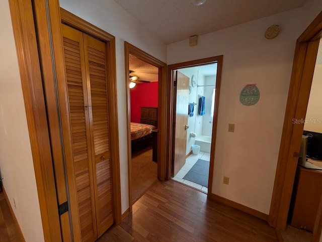 corridor with baseboards and wood finished floors