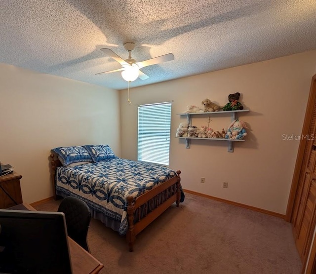 bedroom with ceiling fan, baseboards, a textured ceiling, and light colored carpet