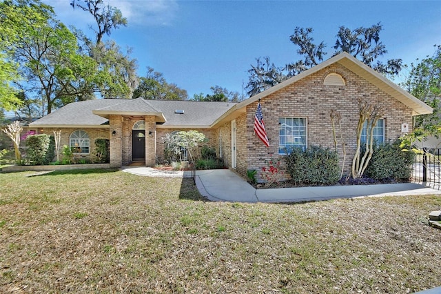 ranch-style house featuring brick siding, a front lawn, and fence