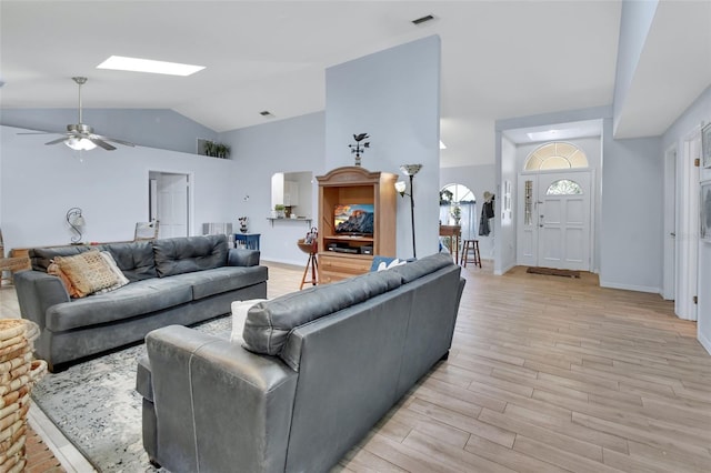 living area with visible vents, light wood-style flooring, lofted ceiling with skylight, ceiling fan, and baseboards