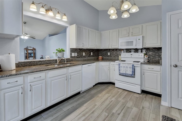 kitchen with white appliances, a sink, and white cabinetry