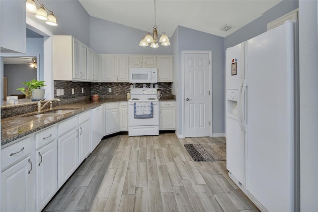 kitchen with lofted ceiling, light wood-style flooring, white appliances, a sink, and decorative backsplash