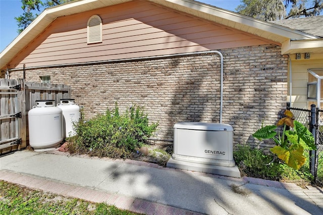 view of property exterior featuring brick siding and fence