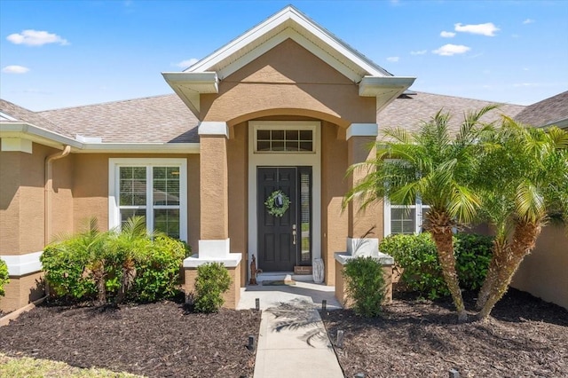 property entrance with a shingled roof and stucco siding