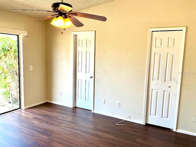 spare room with baseboards, dark wood-type flooring, and a ceiling fan