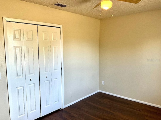 unfurnished bedroom with a ceiling fan, a closet, visible vents, baseboards, and dark wood-type flooring