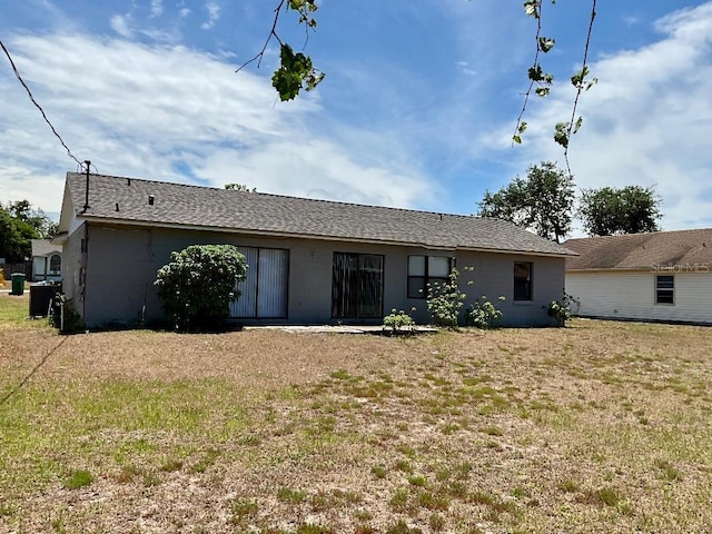 rear view of property featuring a yard and concrete block siding