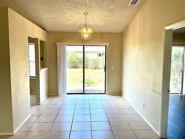 unfurnished dining area featuring an inviting chandelier, a textured ceiling, and light tile patterned flooring