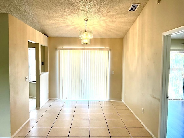 unfurnished room featuring light tile patterned floors, a chandelier, visible vents, and a textured ceiling