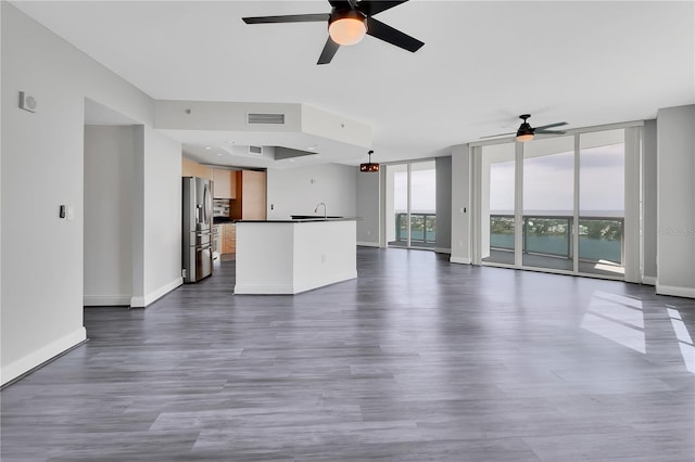 unfurnished living room with baseboards, visible vents, dark wood-style flooring, and expansive windows