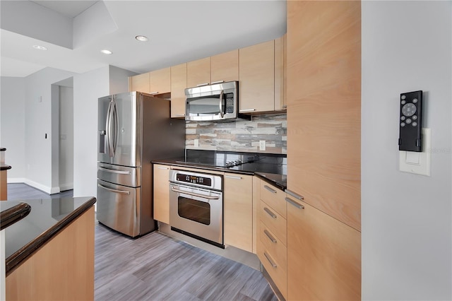 kitchen featuring decorative backsplash, dark countertops, appliances with stainless steel finishes, and light brown cabinets