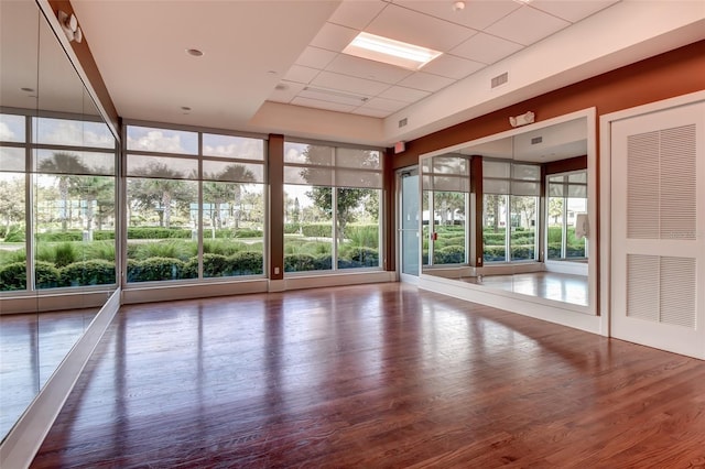 interior space with visible vents, expansive windows, a paneled ceiling, and wood finished floors