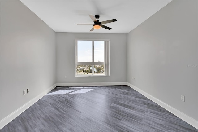 spare room featuring dark wood finished floors, a ceiling fan, and baseboards