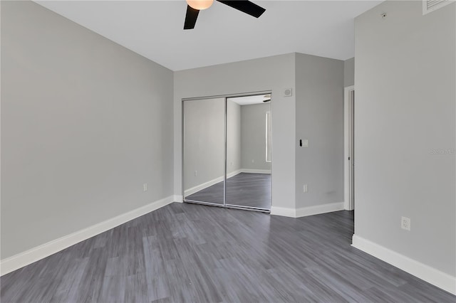 unfurnished bedroom featuring visible vents, baseboards, a closet, dark wood-style floors, and a ceiling fan