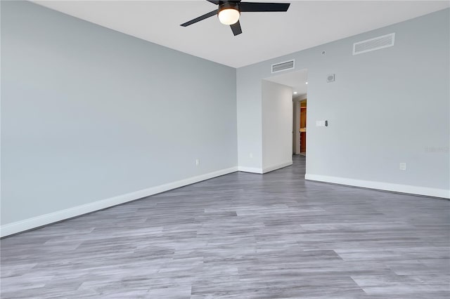 spare room featuring a ceiling fan, wood finished floors, baseboards, and visible vents