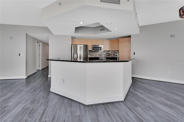 kitchen featuring dark countertops, visible vents, backsplash, light brown cabinets, and appliances with stainless steel finishes