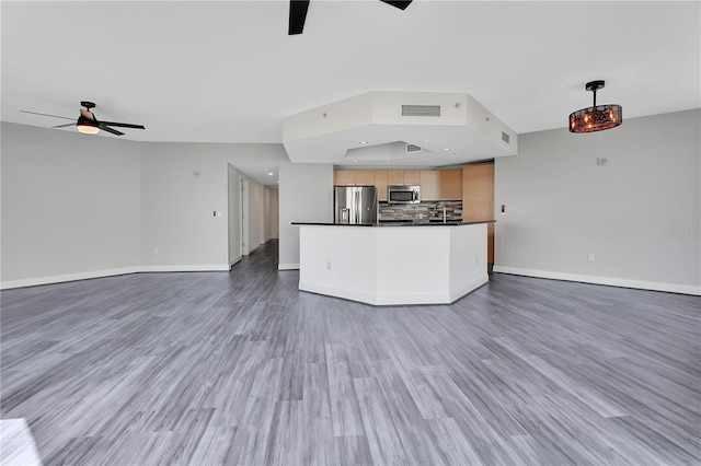 kitchen with dark countertops, a ceiling fan, open floor plan, and appliances with stainless steel finishes