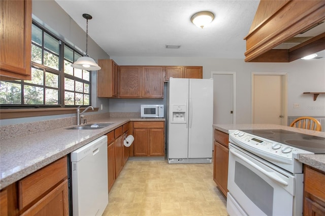 kitchen with decorative light fixtures, brown cabinets, white appliances, and a sink