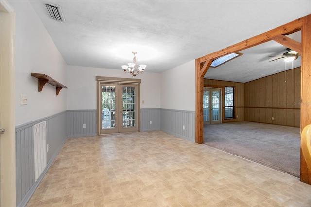 spare room featuring visible vents, a textured ceiling, french doors, an inviting chandelier, and wainscoting