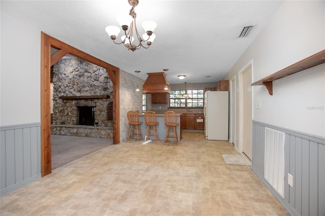 kitchen featuring visible vents, pendant lighting, freestanding refrigerator, and a wainscoted wall