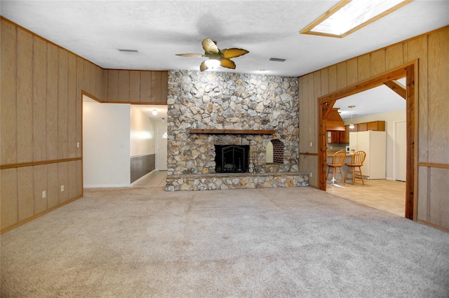 unfurnished living room with visible vents, a fireplace, a ceiling fan, and carpet