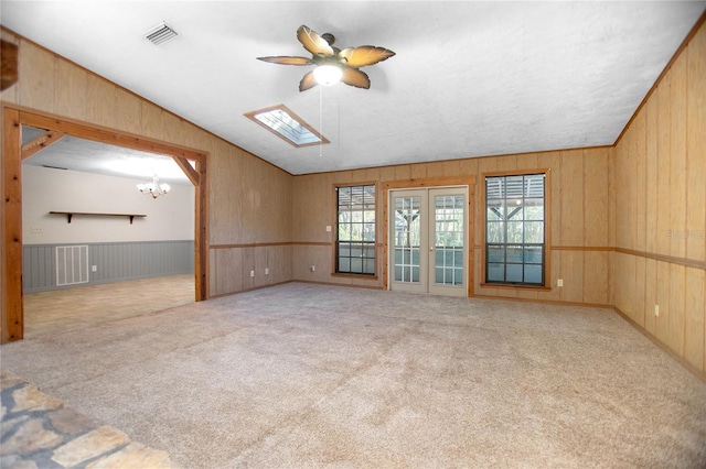 unfurnished room featuring vaulted ceiling with skylight, visible vents, carpet flooring, and a healthy amount of sunlight