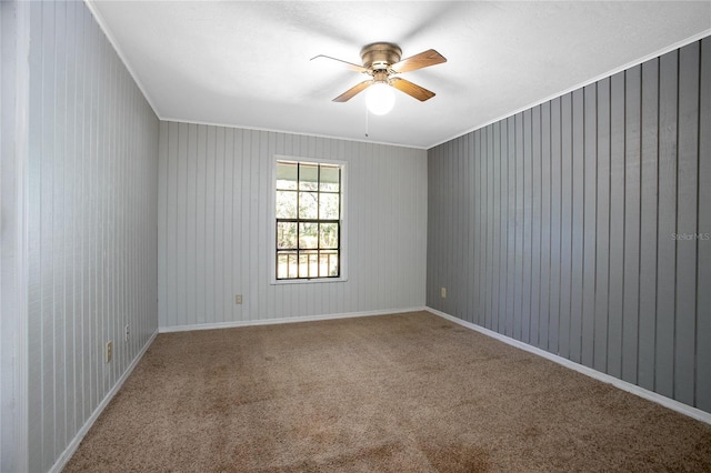 carpeted empty room with baseboards, a ceiling fan, and ornamental molding