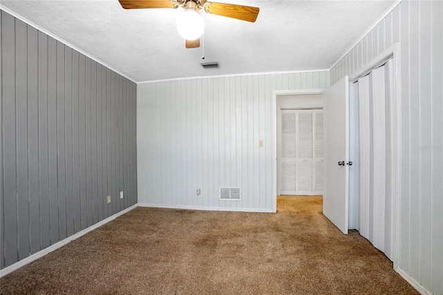 spare room with visible vents, carpet, crown molding, and a ceiling fan