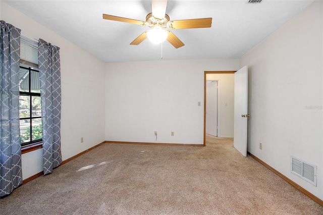 spare room featuring ceiling fan, baseboards, visible vents, and light carpet